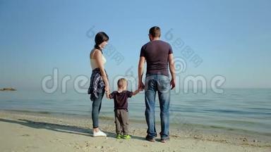 一个幸福的家庭站在大海前面。 海边的父母<strong>溺爱孩子</strong>. 慢动作
